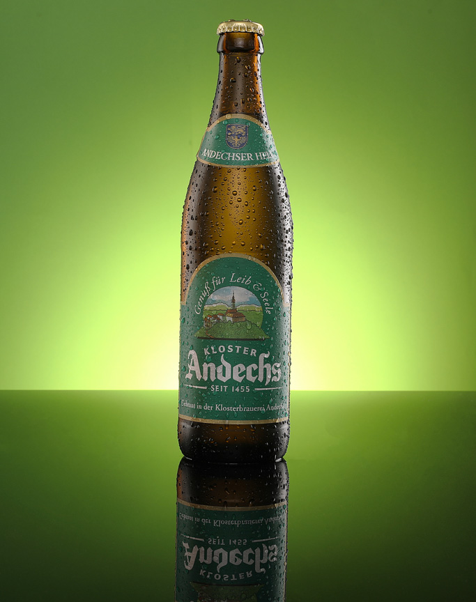 Kloster Andechs Helles bottle glowing against a vivid green studio backdrop with mirror reflection
