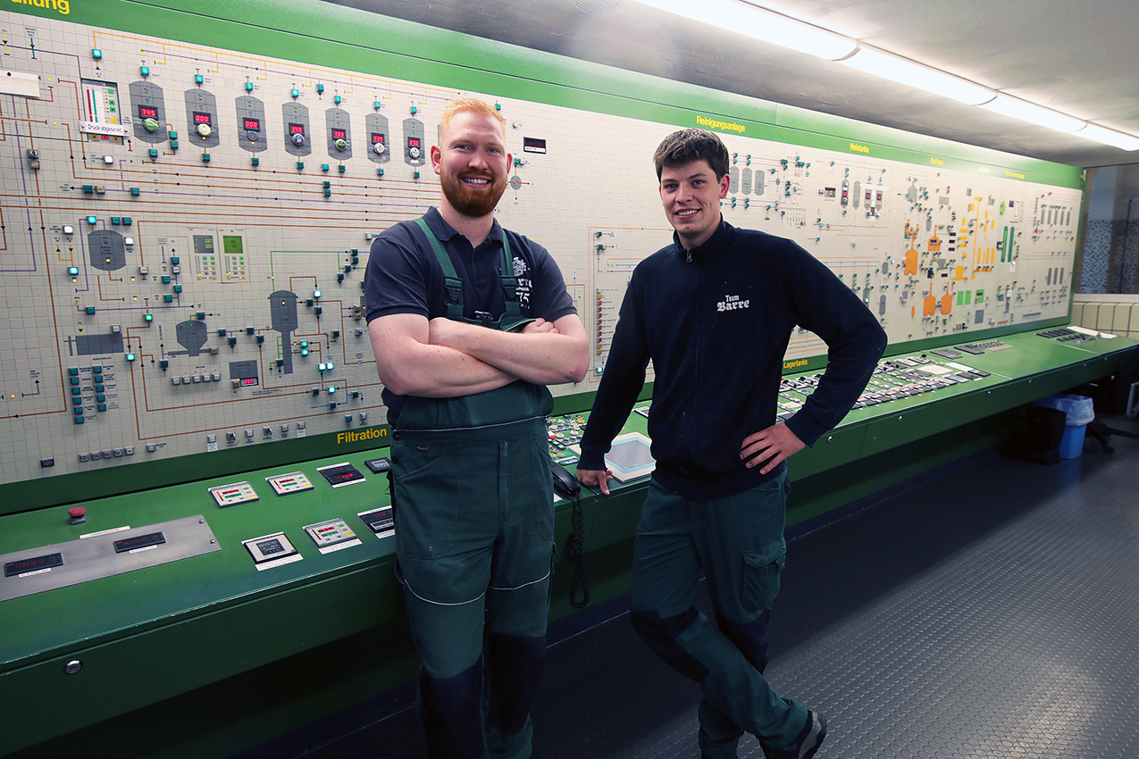 Two Barre brewery workers standing together in front of the large brewery control panel