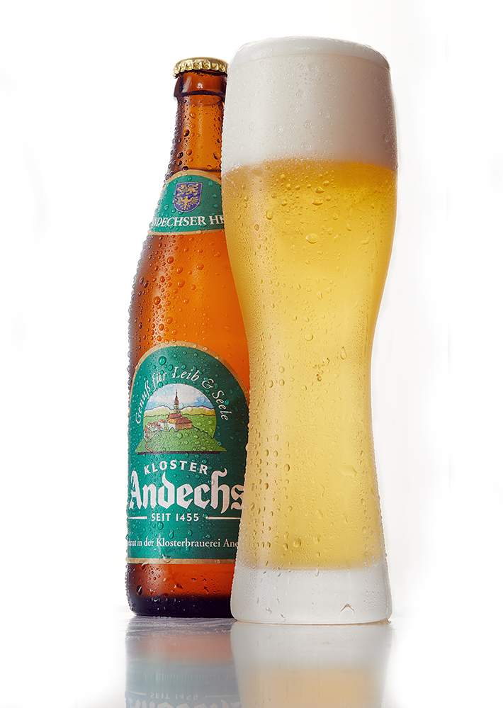 Kloster Andechs bottle beside a tall Weissbier glass on a clean white background
