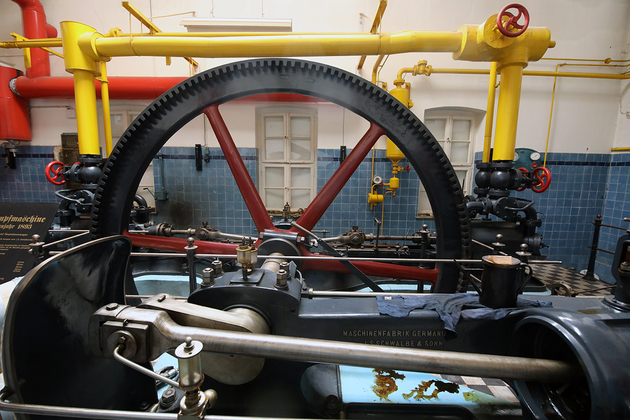 The historic steam engine of 1893 with its large flywheel and painted pipework