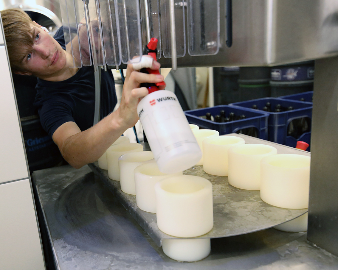 A young brewer spraying and preparing the bottling machine before filling begins