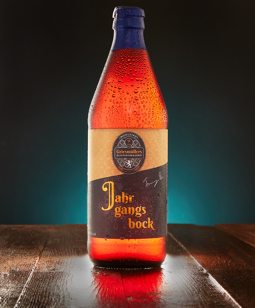 Griesmüllers Jahrgangsbock bottle on a wet wooden table against a teal backdrop