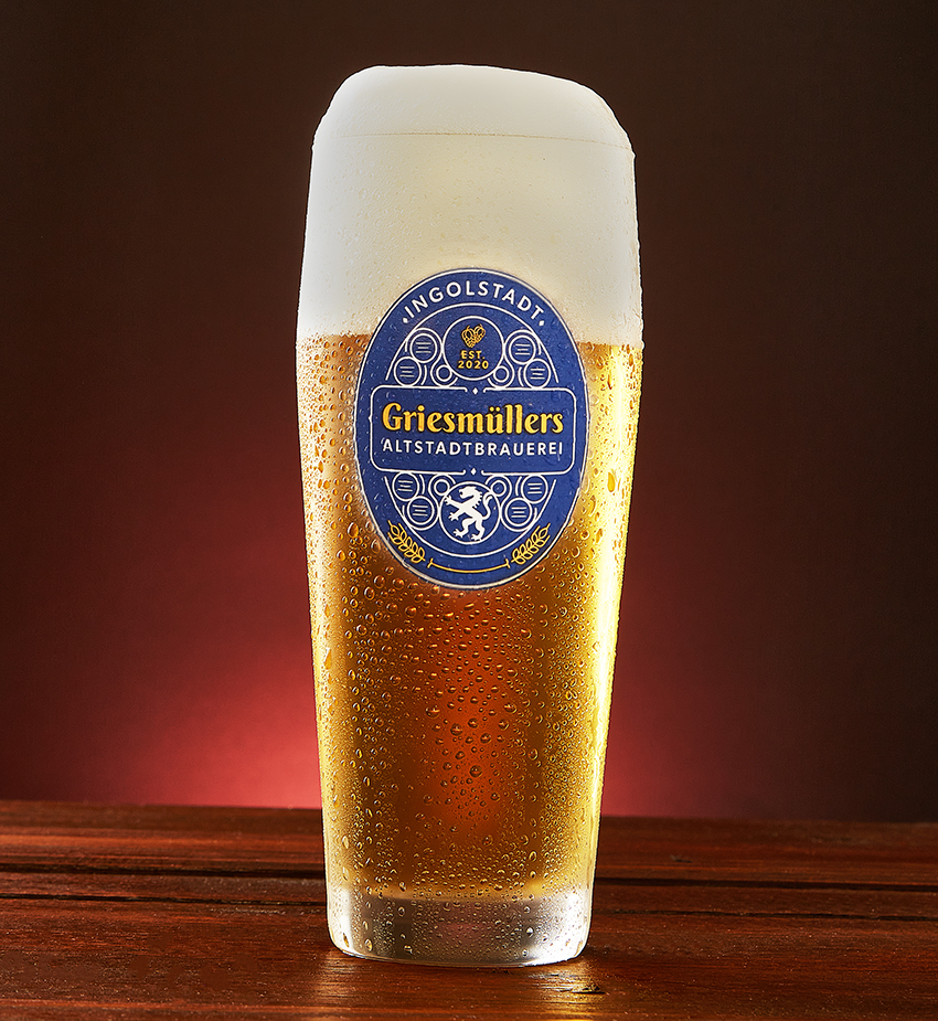 Griesmüllers Pils glass with thick foam head against a glowing red background
