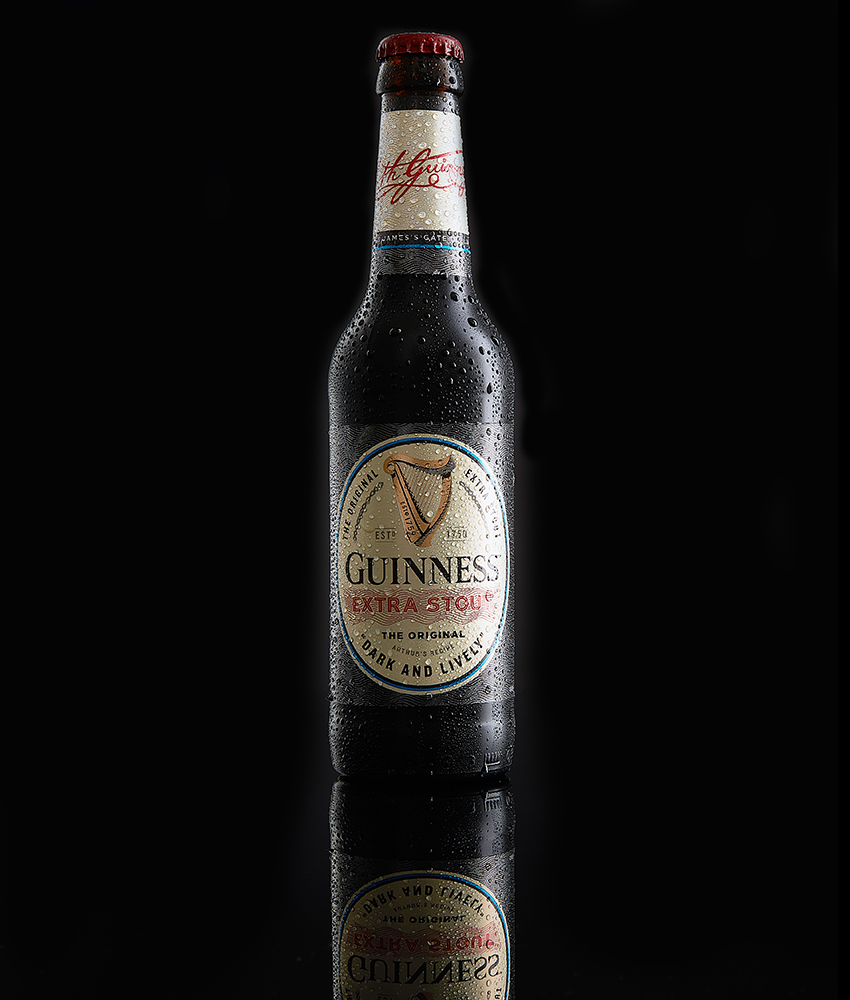 Guinness Extra Stout bottle photographed against a rich black backdrop