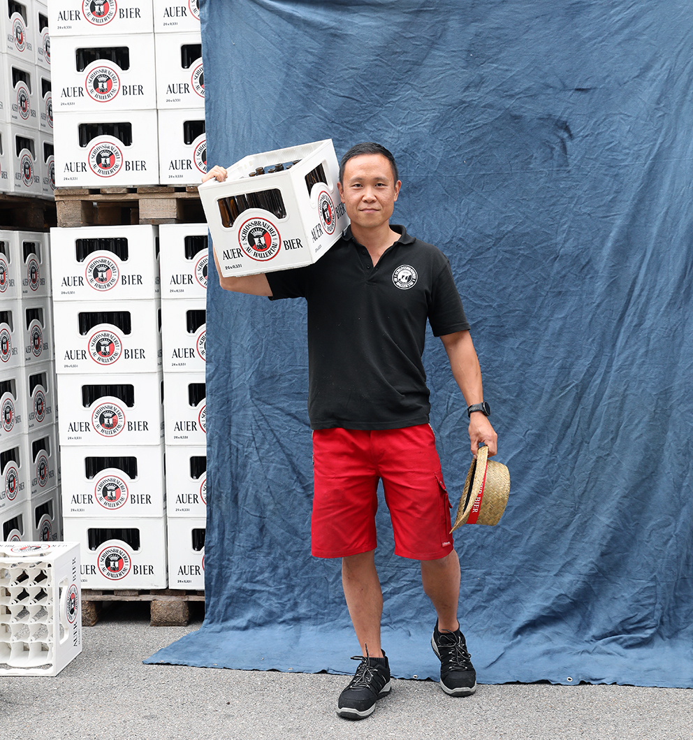 A brewer carrying a full crate of Auer Bier on his shoulder