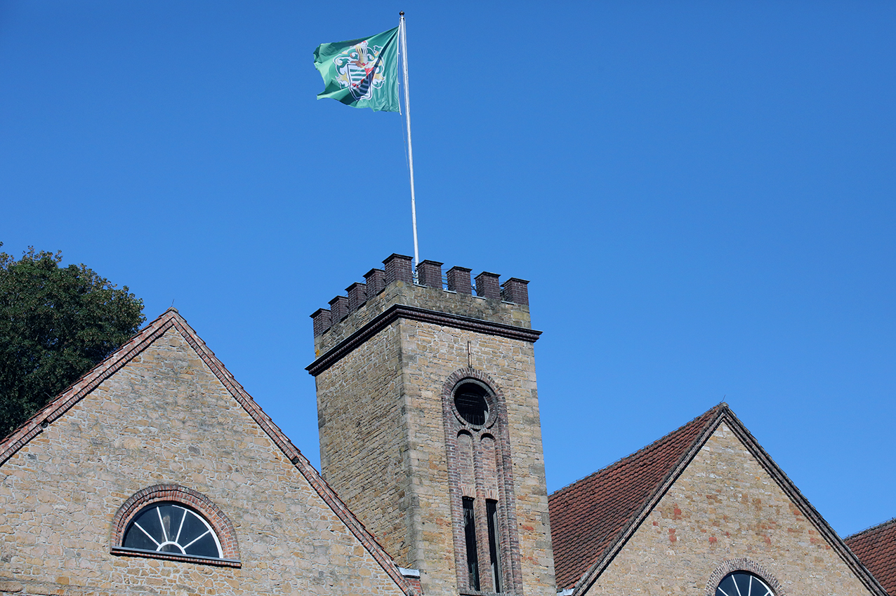 The historic stone brewery tower of Privatbrauerei Ernst Barre flying the family flag against a clear blue sky