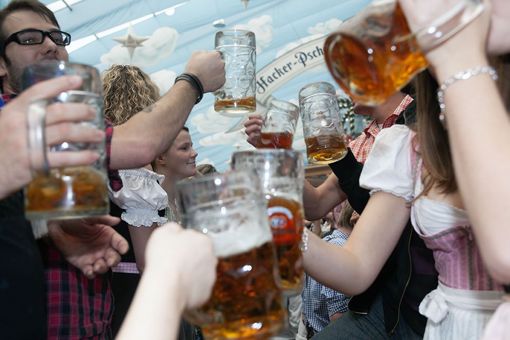 Guests raising litre beer steins together inside an Oktoberfest tent