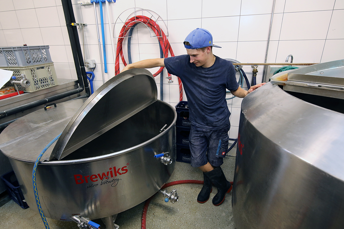 A young brewer opening the lid of the Brewiks mash tun