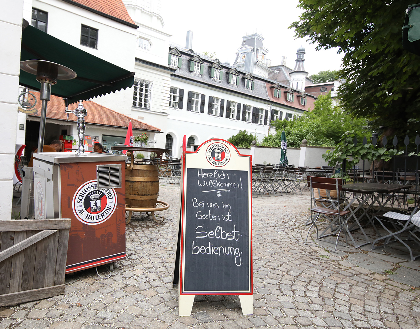 The brewery beer garden with a Schlossbrauerei tap cart and a welcome chalkboard