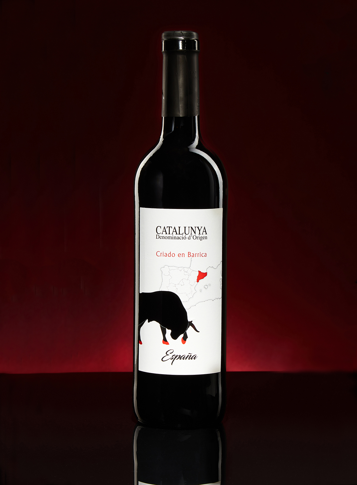 A Catalunya Criado en Barrica red wine bottle against a deep red backdrop