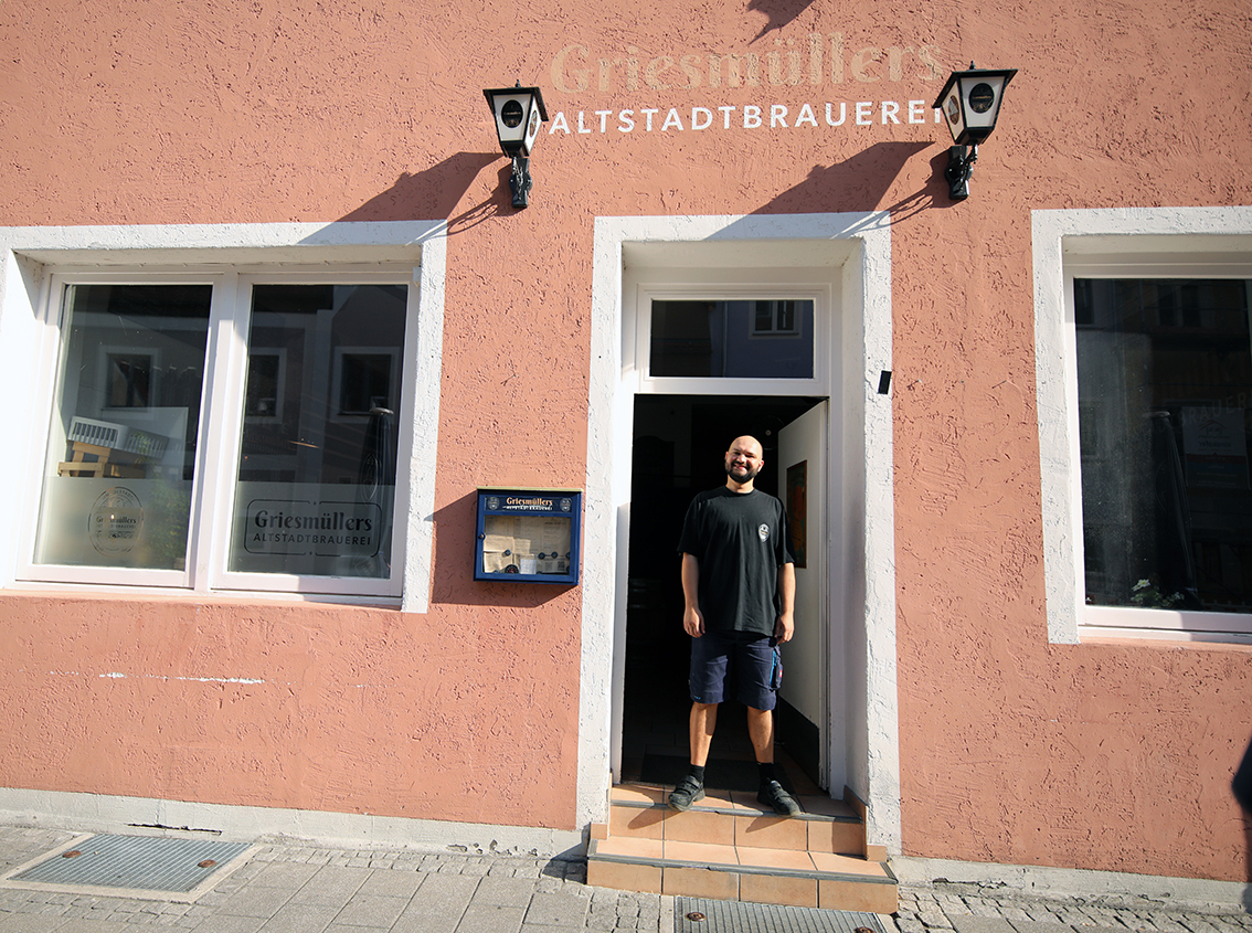 A brewer standing in the doorway of the pink Griesmüllers Altstadtbrauerei building