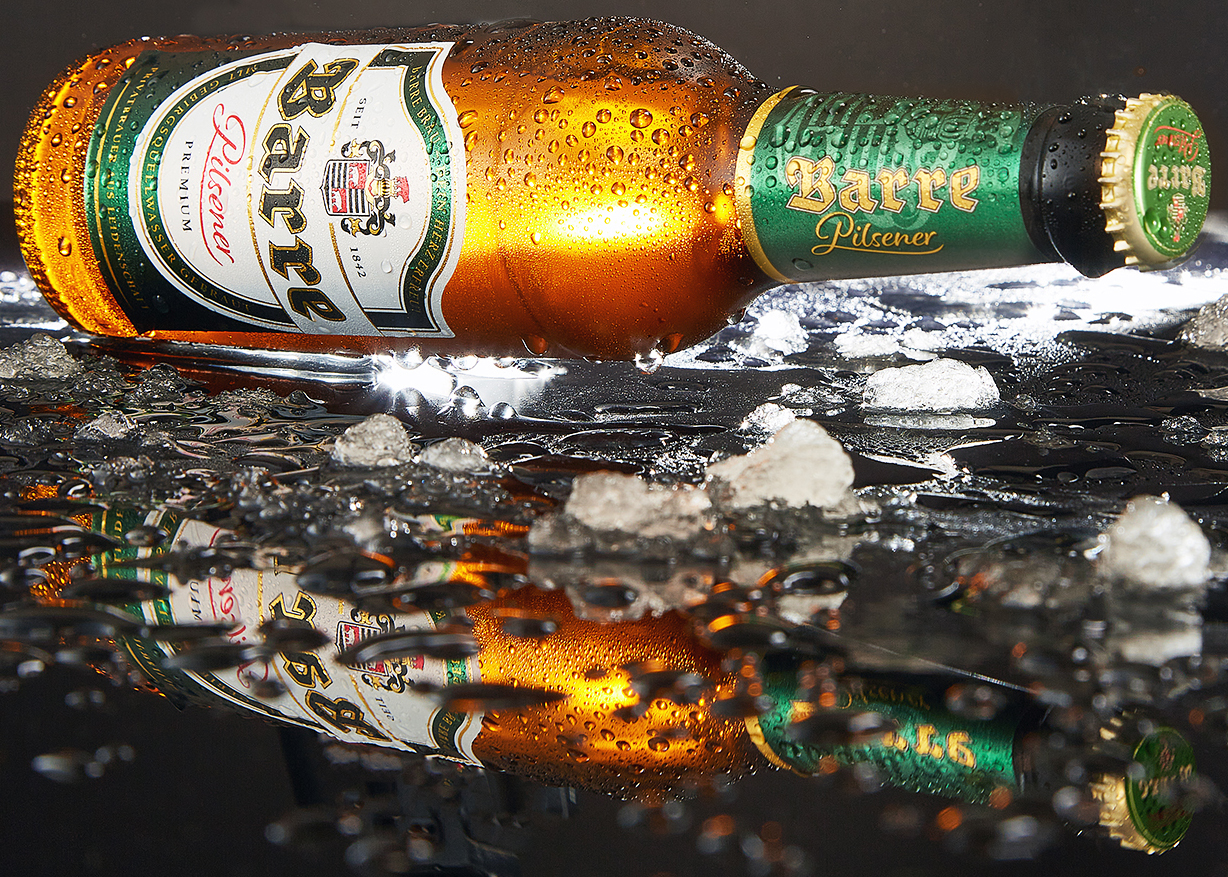 Barre Pilsener bottle lying on crushed ice with condensation and reflection