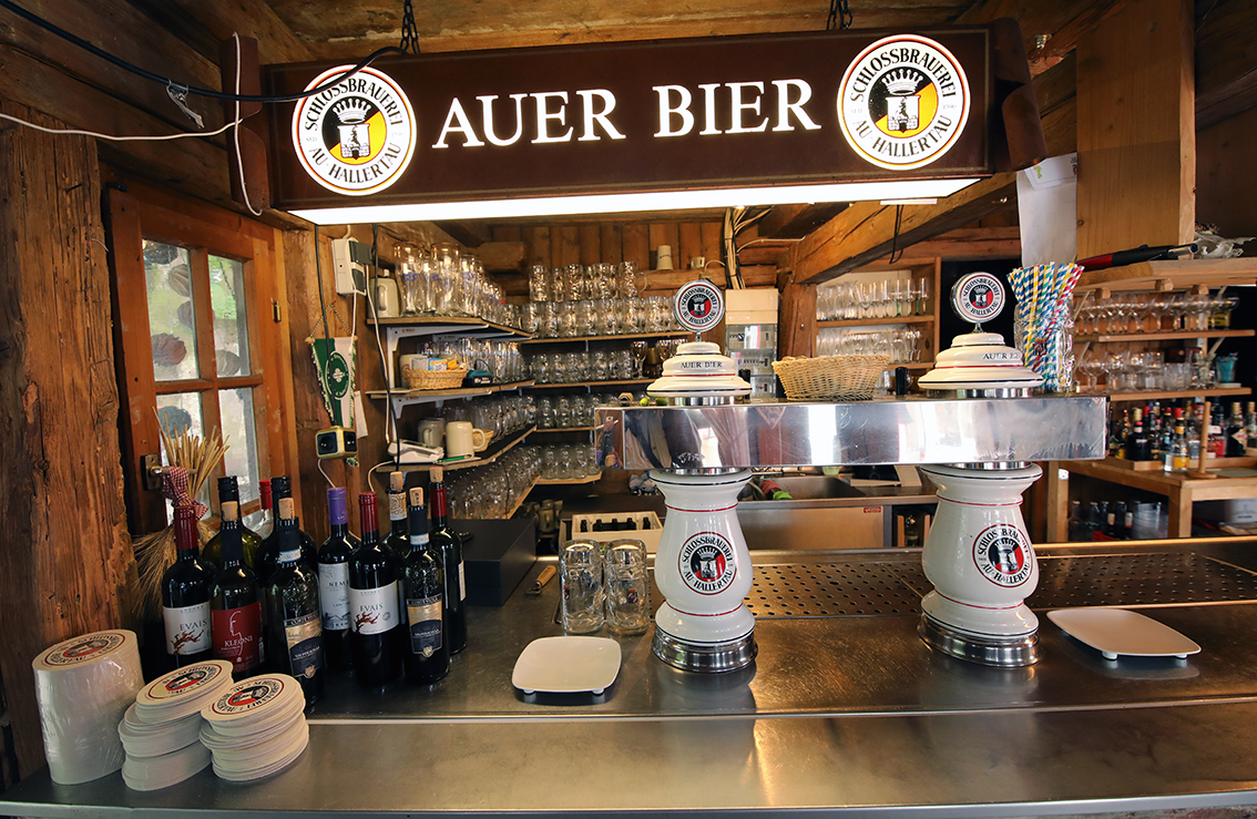 The Auer Bier bar counter with ceramic taps, glasses and an illuminated brewery sign