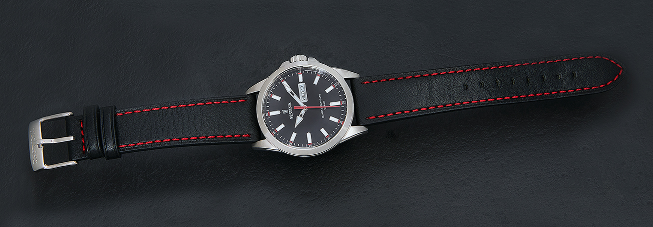 Festina watch laid flat with full black leather strap visible on dark slate