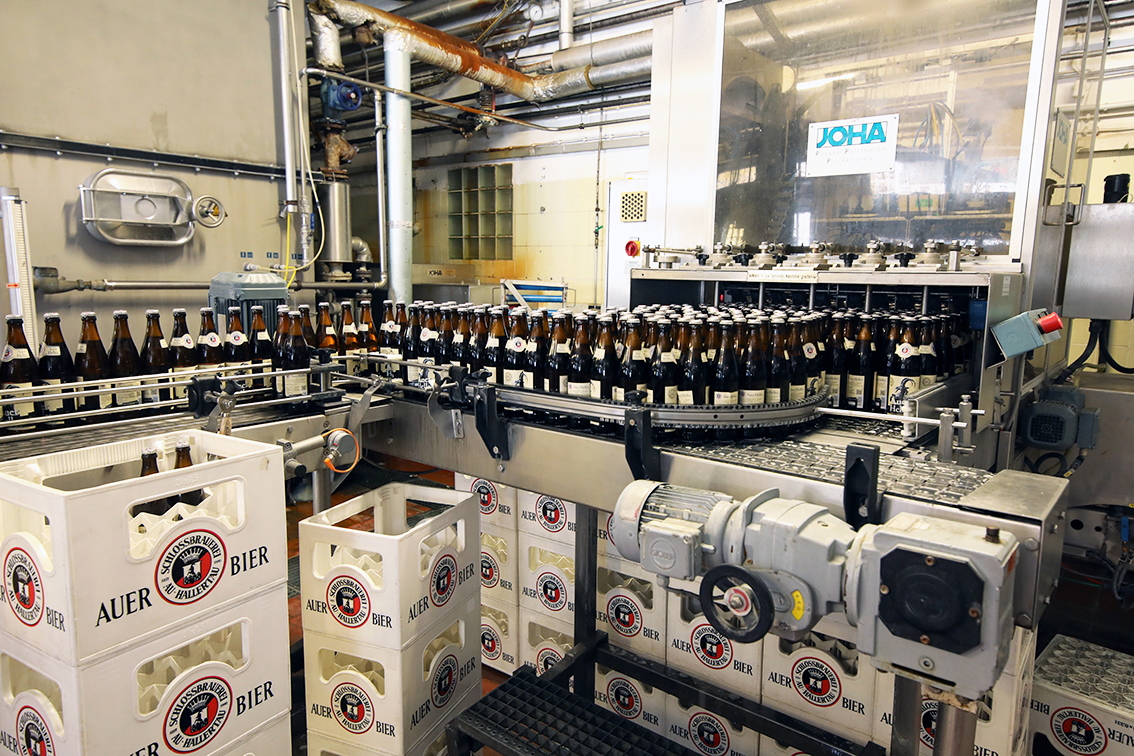 The bottling line in full run with Auer Bier crates stacked beside the machinery